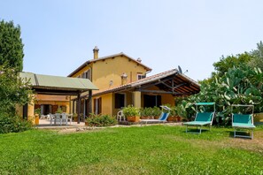 Ein zweistöckiges Haus mit einer Terrasse, Gartenmöbeln und einem Garten.