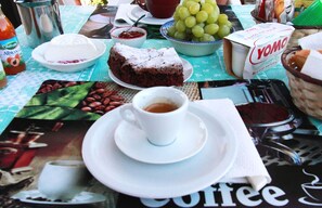 A table with a coffee cup, a plate of cake, a bowl of grapes, and a YOMO yogurt container. - Le Torrette Etrusche Room 6 – Comfort and Relaxation in Capalbio (Capalbio)