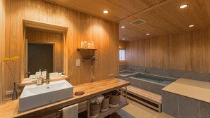 Une salle de bain en bois avec un grand lavabo, un miroir, un meuble-lavabo, une baignoire et une étagère contenant des articles de toilette.