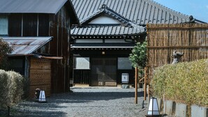 Il s’agit d’un bâtiment japonais traditionnel, doté d’un toit recouvert de tuiles, d’une structure en bois et d’un chemin de gravier menant à l’entrée.