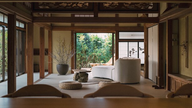 Une pièce de style japonais traditionnel, avec un sol recouvert de tatamis, une table basse et une vue sur un jardin.