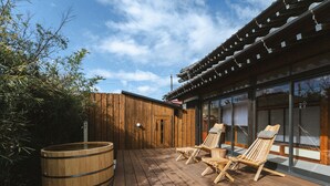 Une terrasse en bois avec des chaises longues et un tonneau en bois.