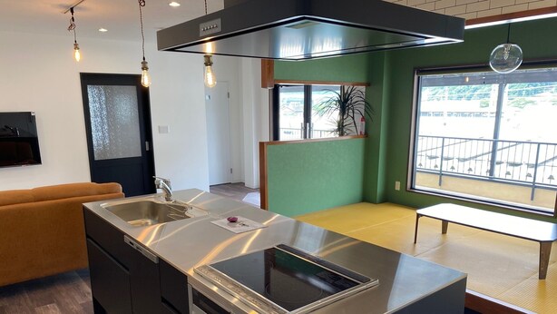 A modern kitchen with a central island, stainless steel appliances, and pendant lighting. - Irorian (Kamakura)