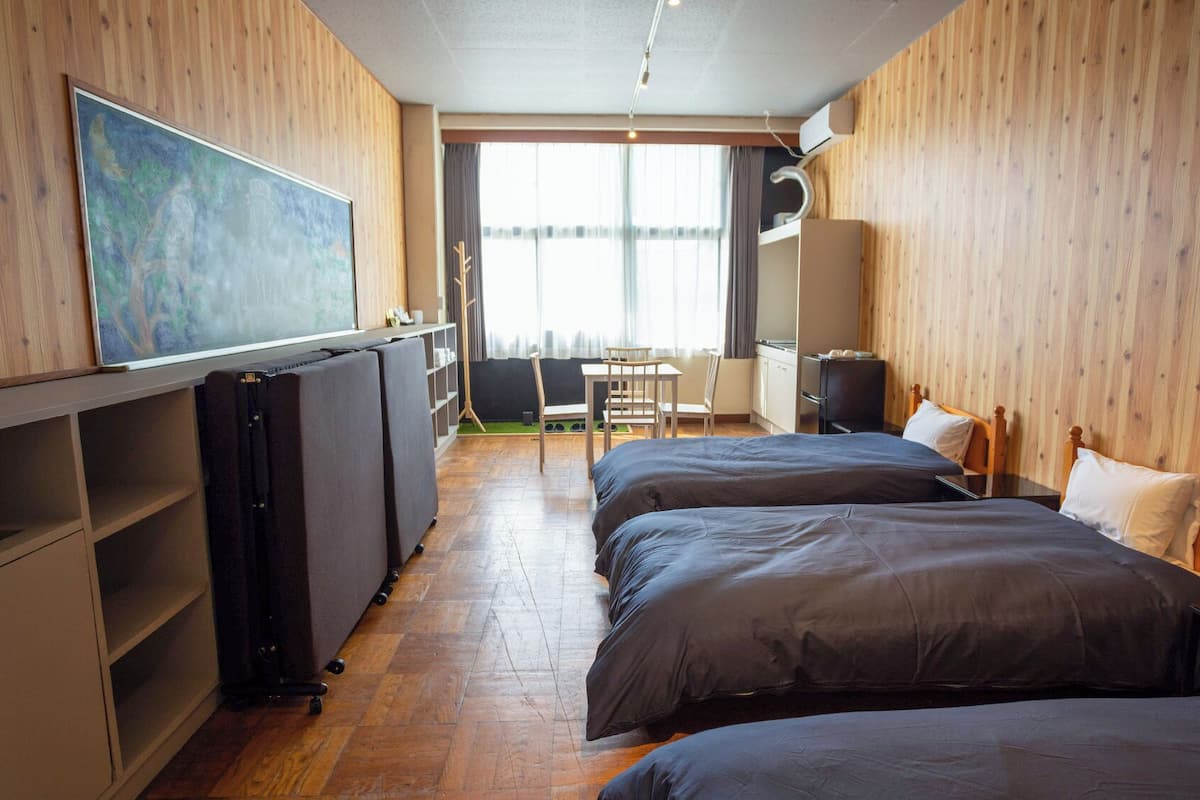 A hotel room with two beds, a desk, a chair, a radiator, and a painting on the wall.