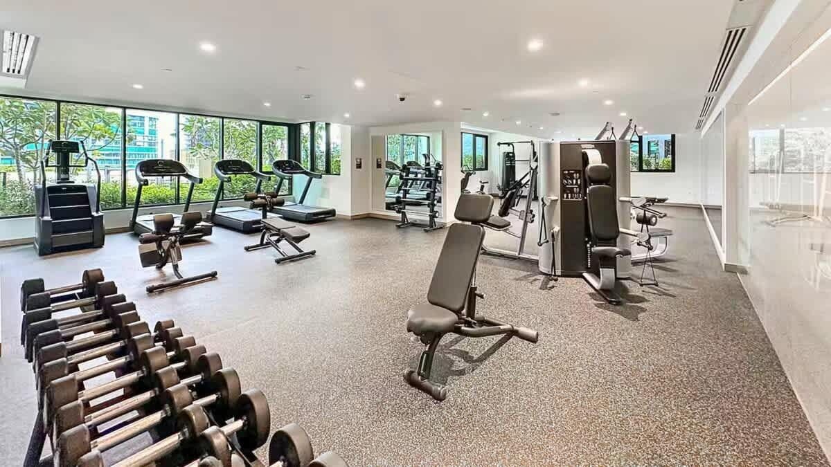 Un gimnasio moderno con cintas de correr, máquinas de pesas y pesas sueltas.
