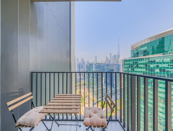 Ein Balkon mit Blick auf eine Stadtansicht, inklusive Tisch und Stühlen, und ein Gebäude, auf dem der Name 'OMNIAT' sichtbar ist.
