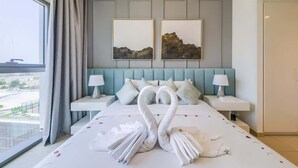 Camera d'albergo con un letto grande, due comodini, una testiera con un dipinto che raffigura un paesaggio e vista sull'esterno.