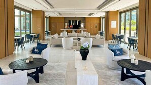 Un'ampia hall con diverse zone relax, un caffè centrale e grandi finestre che offrono luce naturale.