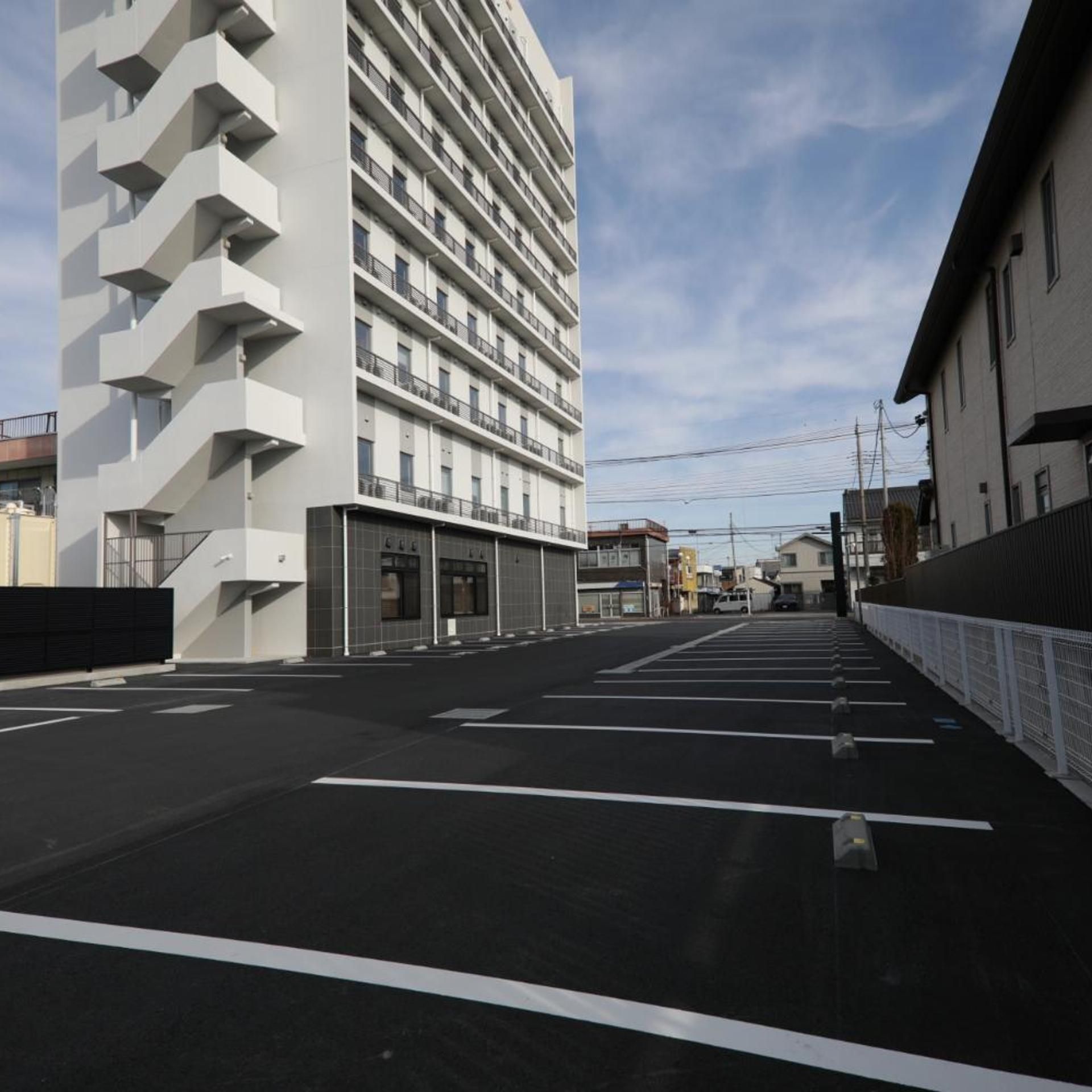 A multi-story building with a modern design, featuring a parking lot in front.