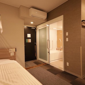 Ein Hotelzimmer mit Bett, einem Schrank mit Spiegel und einer Duschkabine.