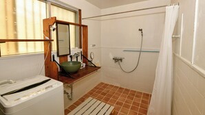 Un baño con ducha, lavamanos y espejo, y un inodoro.