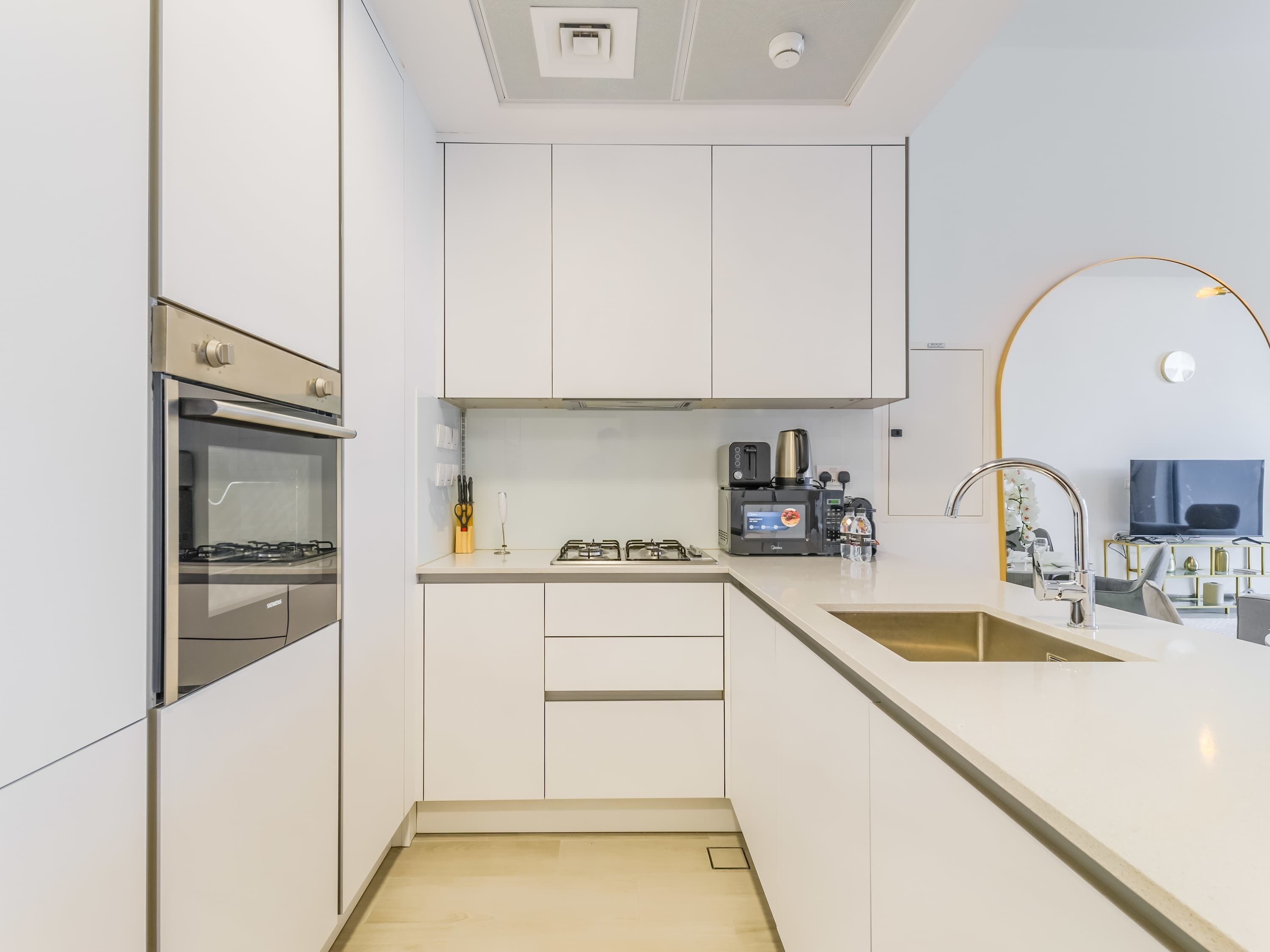 Eine moderne Küche mit weißen Schränken, einem Backofen, einem Gasherd und einer Kaffeemaschine.