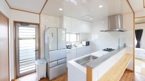 A modern kitchen with white cabinets, a stainless steel refrigerator, a microwave, and a gas stove.