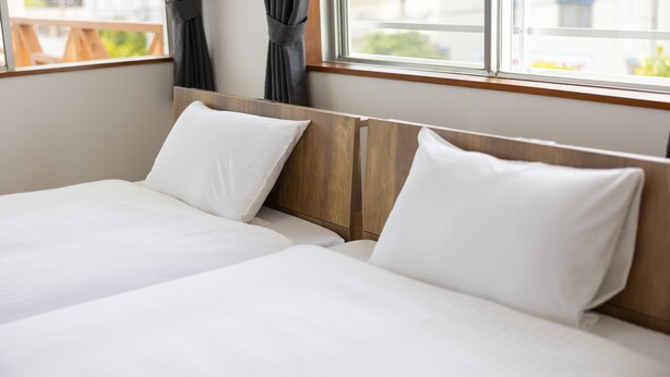 A double bed with white linens and a wooden headboard in a hotel room.