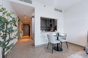 A modern kitchen with a dining area, a plant, and a hallway leading to another room. - Brand New, Luxury Furnished 1BR, Prime Location (Dubai)