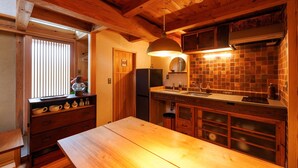 Una cocina de madera con una mesa grande, un refrigerador y un salpicadero de azulejos.