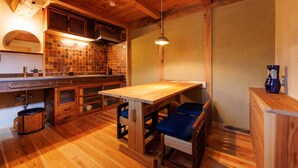 Una cocina rústica con armarios de madera, salpicadero de azulejos, una mesa de comedor de madera y sillas con cojines azules.