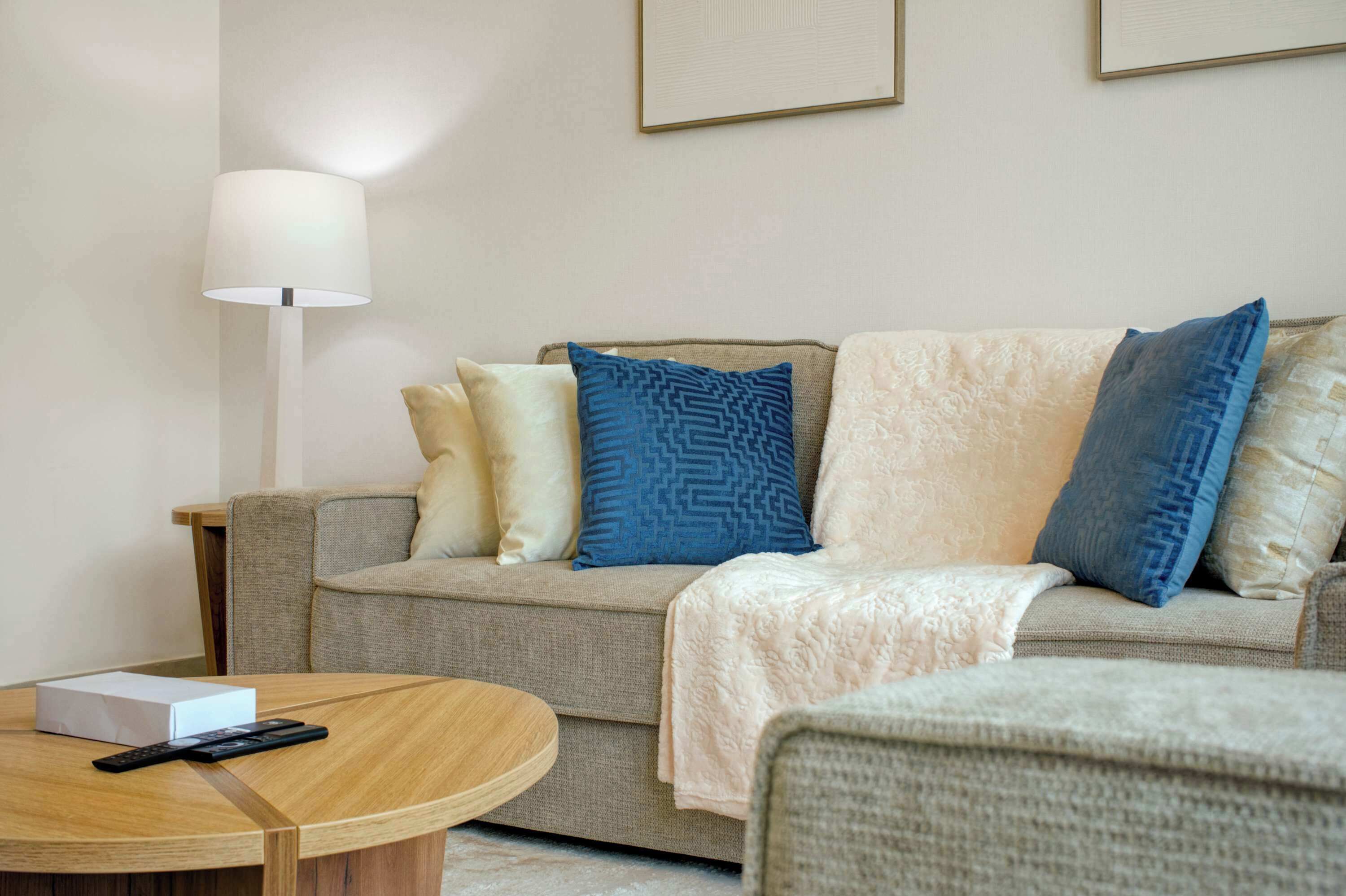 Ein Wohnzimmer mit einer Couch, einer Lampe und einer Fernbedienung auf einem Tisch.