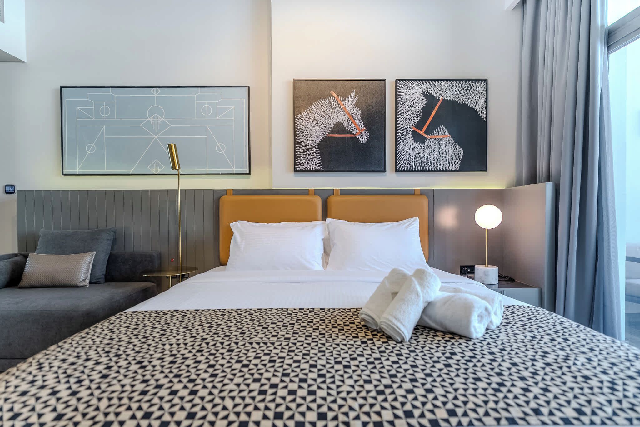 Une chambre d’hôtel avec un lit, un canapé et des œuvres d’art accrochées au mur.