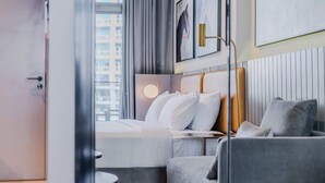 Una habitación de hotel moderna con una cama, un sofá, una mesa redonda y vistas a la ciudad.