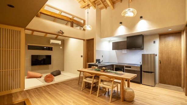A modern kitchen with a dining area, wooden beams, and a TV mounted on the wall. - B/C Hotel Naha Rent-a-car Hotel (Ishigaki)