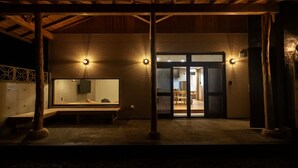 A covered outdoor area with a bench, a wall-mounted mirror, and a door leading to an interior space. - B/C Hotel Naha Rent-a-car Hotel (Ishigaki)