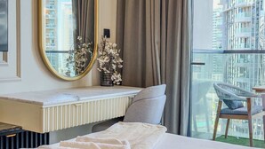 Een moderne hotelkamer met een groot bed, een nachtkastje, een spiegel en uitzicht op de stad door grote ramen.