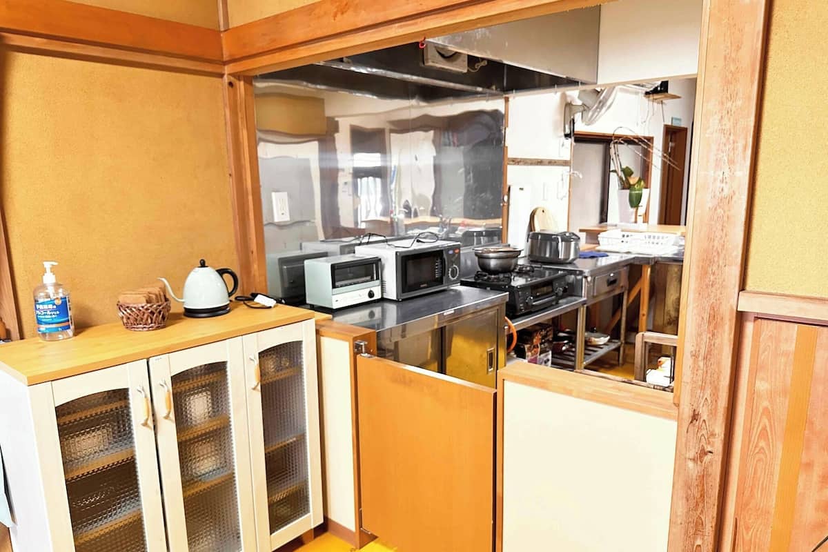 A compact kitchen with a microwave, toaster, and stove, wooden cabinets, and a small countertop.