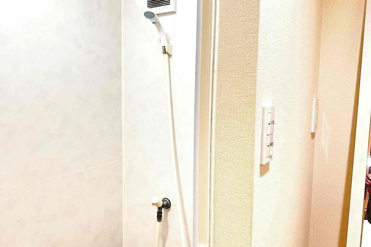 A bathroom with a shower, a towel rack, and a power outlet.