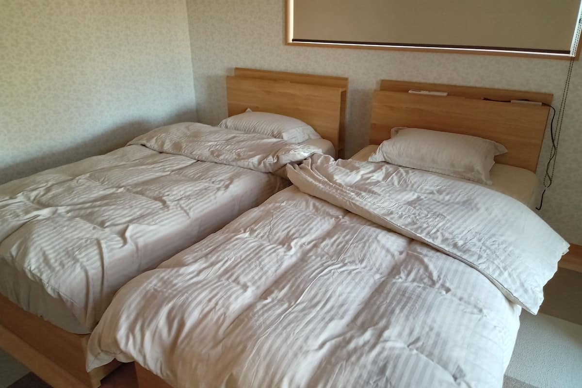 Una cama doble con cabecera de madera, una mesita de noche y una lámpara de pared.