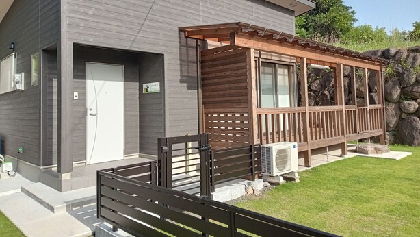 Un bâtiment moderne doté d’une terrasse en bois, d’une porte et d’un appareil de climatisation.