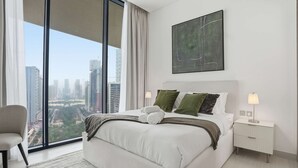 Une chambre moderne avec un grand lit, une table de chevet, une chaise et une vue sur la ville.
