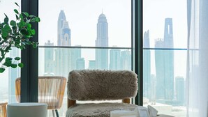 Une chambre d’hôtel moderne avec vue sur les gratte-ciel de la ville, un fauteuil confortable, un bol blanc et une boîte de mouchoirs.