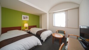 Ett hotellrum med två sängar, ett skrivbord, en stol, en TV och ett fönster med gardiner.