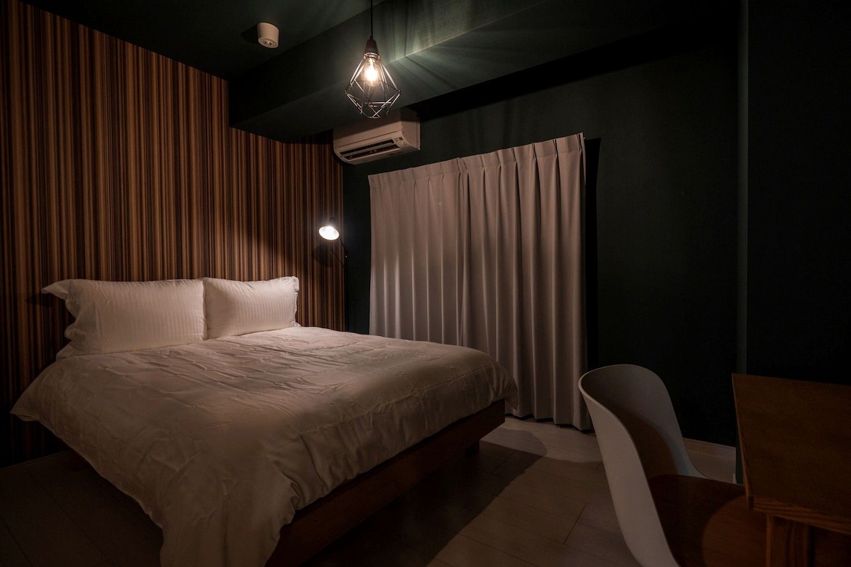 A bedroom with a bed, a desk, and a chair.