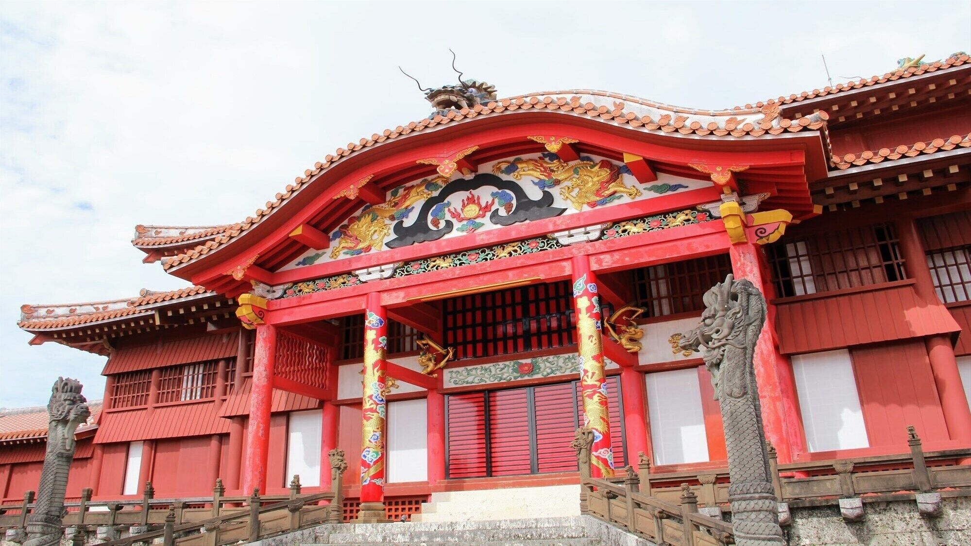 Ein traditionelles chinesisches Gebäude mit roten Wänden, aufwendigen Dachziegeln und dekorativen Drachenreliefs.