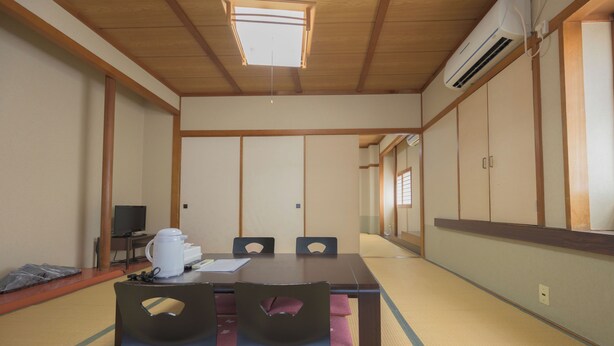 Una habitación tradicional japonesa con suelo de tatami, una mesa baja y un ventilador de techo.