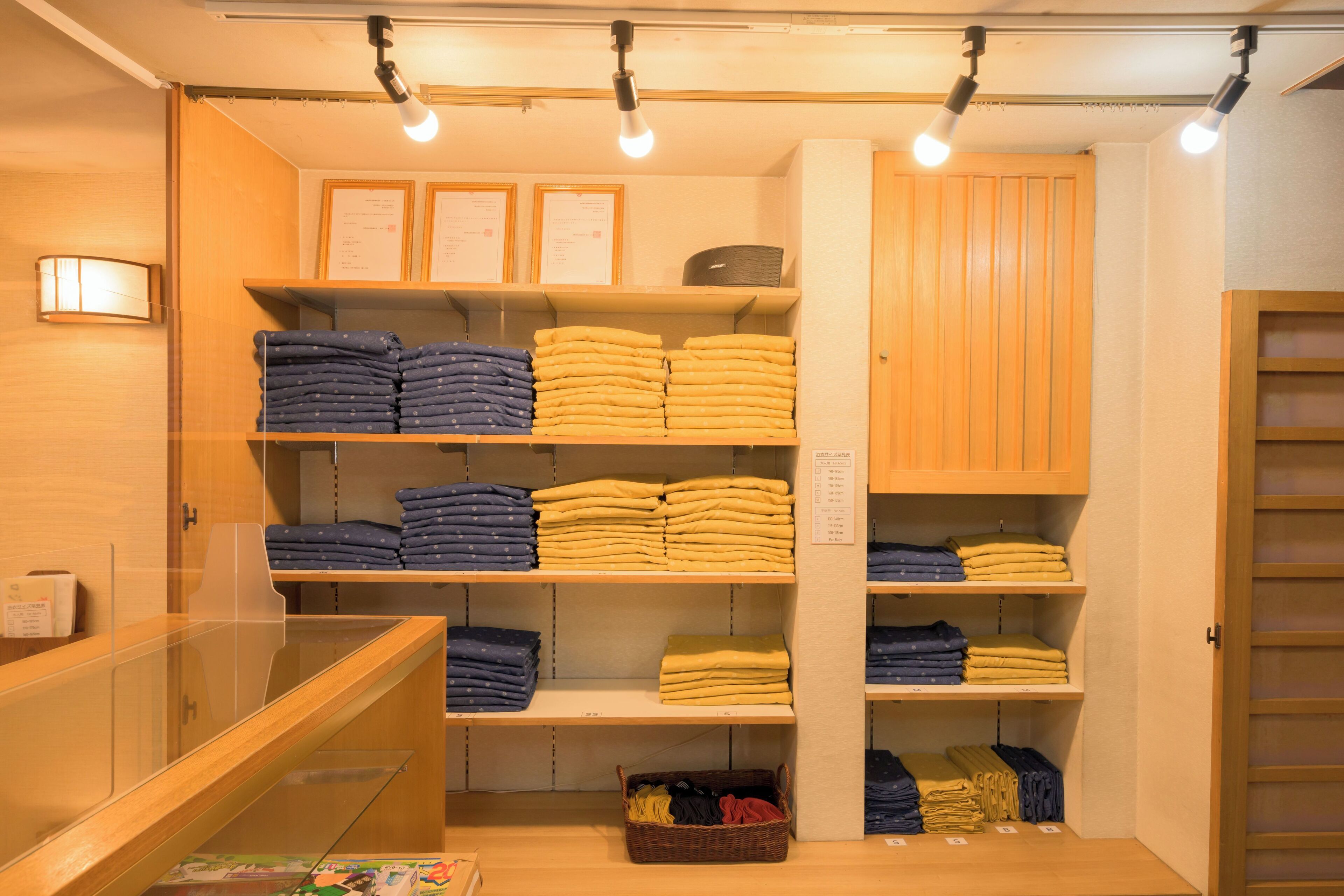 A neatly organized clothing store with shelves of folded garments and a display counter.