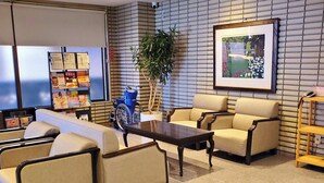 En lobby med reception, siddeområde og et billede i ramme på væggen.