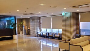 En moderne lobby med receptionsdisk, siddeområde og et stort vindue.