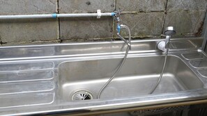 Un lavamanos de acero inoxidable con un solo grifo y una manguera.