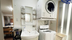 Un bagno d'albergo piccolo ma funzionale, con lavandino, specchio e lavatrice integrata.