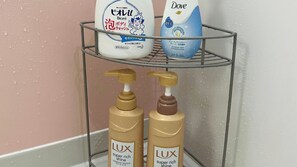 A bathroom shelf with a bottle of Dove soap, a bottle of Lux shampoo, and a bottle of Lux conditioner. - Icony (Miyakojima)