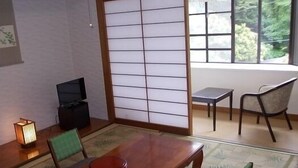 A traditional Japanese-style room with tatami flooring, a low wooden table, and a television. - Merci 0823 (Ito)
