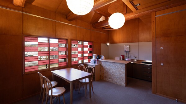 Un interior de madera con comedor, cocina y vista a través de un shoji.