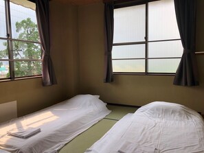 A room with two beds, a window with curtains, and a view of trees outside. - Business Hotel Wakasa (Sayama)