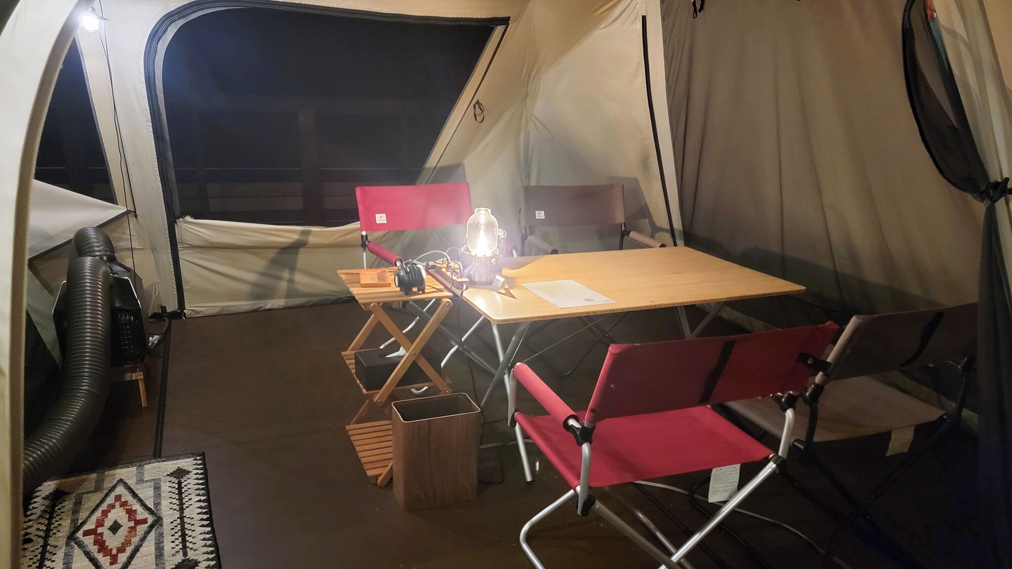 Una tenda con tavolo, sedie e una lampada.