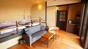 A compact room with a bunk bed, a sofa, a wooden table, and a kitchen area. - Kougetsu Okuyamada Onsen (Takayama)