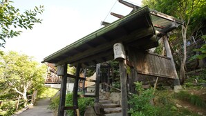 A wooden staircase with a metal roof, surrounded by greenery and trees. - Kougetsu Okuyamada Onsen (Takayama)