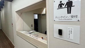 A reception area with a check-in/reception sign, a small window, and a wall-mounted intercom. - Lodges Daikoku (Toyama)